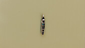 Aerial view of a solitary canoe cuts through the still, tan waters, a single figure aboard, Rimi, katsina, Nigeria.