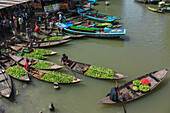 Barishal, Bangladesh - 09 August 2018: View of boats laden with vibrant green produce clustered along the waterway, reflecting the bustling river market's lively trade and earthy tones.