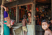 Mirsharai, Bangladesh - 21 October 2019: View of a rustic shop, its weathered corrugated walls framing the vibrant chaos of goods within, as children gather around.