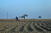 Rangpur, Bangladesh - 01 December 2019: View of a young boy joyfully running with a Bangladesh flag across the vast, ploughed fields, his spirit soaring against the muted, misty horizon.