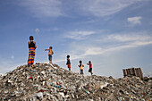 Chittagong, Bangladesch - 09. September 2022: Blick auf spielende Kinder in einer weitläufigen, strukturierten Landschaft aus weggeworfenem Müll vor dem Hintergrund eines entfernten Gebäudes.