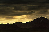 View of dramatic dark clouds loom over the silhouetted jagged peaks of the mountains, creating a landscape of stark contrast and shadowed beauty, Skardu, Gilgit Baltistan, Pakistan.