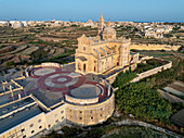 Aerial view of the majestic Ta' Pinu Sanctuary stands proud against the golden landscape, its intricate architecture a beacon of faith and history, Gharb, Gozo, Malta.