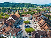 Aerial view of the quaint town square with its red-tiled roofs and the church steeple piercing the skyline, nestled amidst verdant hills, Aarberg, Canton of Bern, Switzerland.