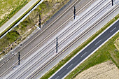 Aerial view of parallel lines of transportation infrastructure contrasting with the natural landscape, including railways and roads, Deutschlandsberg, Steiermark, Austria.