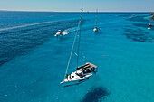 Aerial view of boats sailing on turquoise waters, contrasting against the white hulls under the clear sky, Favignana, Sicily, Italy.