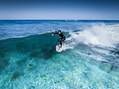 Aerial view of a surfer gliding through turquoise waters, a dance of motion and light captured from above, Gracetown, Western Australia, Australia.