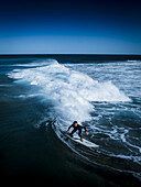 Aerial view of a surfer carving through the turquoise waves, the white foam a stark contrast against the deep blue ocean, Gracetown, Western Australia, Australia.