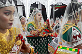 Sylhet, Bangladesh - 08 November 2022: View of young women adorned in vibrant green and gold traditional attire, their hands clasped in prayerful reverence, framed by the intricate white architecture.