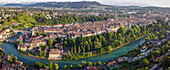 Luftaufnahme des türkisfarbenen Flusses Aare, der sich durch die Stadt schlängelt und die Terrakotta-Dächer der Altstadt sowie das hoch aufragende Münster umspült, Bern, Kanton Bern, Schweiz.