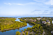 Luftaufnahme des Mwachema-Flusses, auch bekannt als Kongo-Fluss, der sich durch üppig grüne Mangrovenwälder schlängelt und in der Nähe von Strohdächern das türkisfarbene Meer erreicht, Tiwi, Kwale County, Kenia.