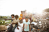 Chattogram, Bangladesch - 04. Oktober 2022: Blick auf Kinder inmitten der rauen Landschaft einer Mülldeponie, wo das Leben aus dem Abfall sprießt, unter einem blassen Himmel.