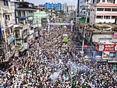 Chattogram, Bangladesh - 16 September 2024: Aerial view of a vibrant procession surging through the city streets, a sea of humanity adorned with green flags beneath the clear sky.