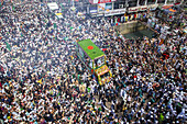 Chattogram, Bangladesh - 16 September 2024: Aerial view of a vibrant procession moving through a dense crowd, with a decorated vehicle as the focal point, creating a sea of motion.