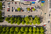 Aerial view of cars neatly aligned in a parking lot next to Nordstan Shopping Centre, with lush green trees lining the streets, Gothenburg, Vastra Gotaland, Sweden.
