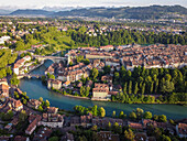 Luftaufnahme der Aare, die sich um die Altstadt mit ihren roten Dächern und Sandsteingebäuden windet, eingerahmt von üppigem Grün und fernen Bergen, Bern, Kanton Bern, Schweiz.