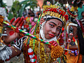 Sylhet, Bangladesch - 08. November 2022: Blick auf eine junge Darstellerin, die mit leuchtendem Rot und Gold geschmückt ist, das Gesicht mit auffälligem Make-up bemalt ist und einen geschmückten Stab hält - ein fesselnder kultureller Ausdruck.