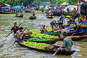 Atghar Kuriana, Bangladesh - 28 July 2017: View of a bustling floating market canal brimming with boats laden with vibrant green fruits, reflecting the lush surroundings and the lively trade..