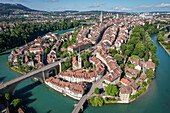 Luftaufnahme der leuchtend türkisfarbenen Aare, die die Altstadt mit ihren roten Ziegeldächern und dem hoch aufragenden Berner Münster umarmt, Bern, Kanton Bern, Schweiz.