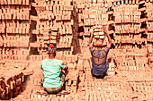 Narsingdi, Bangladesh - 08 December 2024: View of men working among the towering stacks of terracotta bricks, a scene of labor under the warm sun.