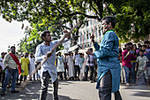 Chattogram, Bangladesh - 29 July 2023: View of two men engaged in a fierce stick fight, surrounded by an animated crowd under the dappled sunlight filtering through lush green trees.