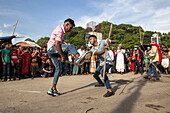 Chattogram, Bangladesh - 29 July 2023: View of two young men engaged in a spirited Lathi Khela match, surrounded by an eager crowd under a bright sky.