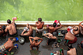 Tongi, Bangladesh - 31 January 2025: Aerial view of men bathing and cleansing themselves by the shimmering, jade-green water edge, their skin glistening under the sunlight.