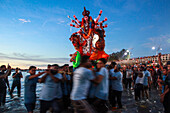 Chittagong, Bangladesh - 05 October 2022: View of a vibrant Durga idol being carried into the water during immersion, with crowds gathered along Sea Beach Road.
