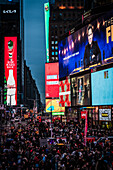 New York, Vereinigte Staaten - 24. Dezember 2023: Blick auf den Times Square, der in das elektrische Licht riesiger Reklametafeln getaucht ist, ein lebendiger Teppich aus Licht und Schatten inmitten der geschäftigen Menschenmenge unter ihm.