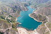 Luftaufnahme des türkisfarbenen Seewassers, das sich durch zerklüftete Berge schlängelt, ein Wandteppich aus erdigen Braun- und Grüntönen unter einem weiten Himmel, Dagestan, Russland.
