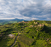 Luftaufnahme der alten Festung Rocca di Tentennano und des Dorfes auf einem üppig grünen Hügel unter einem dramatischen Himmel, Castiglione d'Orcia, Toskana, Italien.
