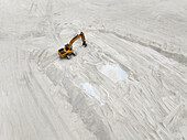 Aerial view of a lone yellow excavator carving furrows into the stark, white land reclamation area, Gulhi, South Male Atoll, Maldives.