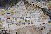 Luftaufnahme von weißen Marmorterrassen, die in den Berghang gehauen wurden, ein Zeugnis der menschlichen Industrie in der zerklüfteten Landschaft von Carrara, Toskana, Italien.