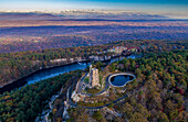 Luftaufnahme des steinernen Turms des Mohonk Preserve, der sich von den bunten Herbstblättern und dem ruhigen Wasser des Sees abhebt, New York, Vereinigte Staaten.