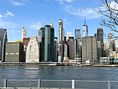 Blick auf glänzende Wolkenkratzer, in denen sich der strahlend blaue Himmel und das plätschernde Wasser spiegeln, wo die Moderne auf die heitere Umarmung der Natur trifft, New York, New York, Vereinigte Staaten.