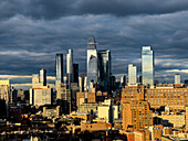 Blick auf das Sonnenlicht, das die Wolkenkratzer küsst, während Sturmwolken über dem architektonischen Wandteppich von Hudson Yard, New York City, New York, Vereinigte Staaten, aufziehen.