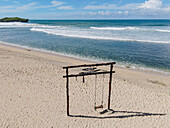 Aerial view of a rustic wooden swing set standing on the pristine sands meeting the turquoise ocean, Yogyakarta, Indonesia.
