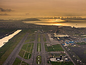 Aerial view of the Navi Mumbai International Airport glimmers under the sun's hazy glow, a modern marvel amidst the sprawling cityscape, Navi Mumbai, Maharashtra, India.