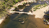 Aerial view of a river flowing gently around a small concrete structure, the water reflecting the sky above, Gashaka, Gashaka, Nigeria.
