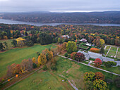 Luftaufnahme des leuchtenden Herbstlaubs, das die Landschaft entlang eines ruhigen Flusses in eine malerische Szene verwandelt, Garrison, New York, Vereinigte Staaten.