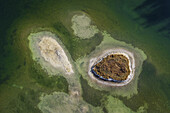 Luftaufnahme von kleinen Inseln mit kontrastierenden Grün- und Brauntönen, umgeben von den ruhigen Gewässern des Misurina-Sees, Misurina, Belluno, Italien.
