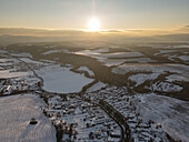 Aerial view of the village nestled in the snow-covered valley, where the last light kisses the mountaintops, creating a serene landscape, Cerín, Banskobystrický kraj, Slovakia.