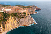 Aerial view of dramatic cliffs meet the vast ocean near the lighthouse at Pedra da Mua, a coastal vista of natural beauty, Pedra da mua lagosteiros, Setúbal, Portugal.