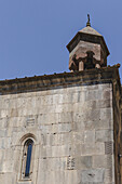 View of the ancient stone structure with its bell tower rising against the clear blue sky, a testament to history and faith, Geghard Monastery, Mets Gilanlar, Ararat Province, Armenia.