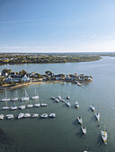 Luftaufnahme von Yachten, die in den ruhigen azurblauen Gewässern nahe der Küste ruhen, mit der entfernten grünen Küstenlinie, die eine ruhige Szene schafft, Presqu'île de Conleau, Bretagne, Frankreich.