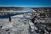 Luftaufnahme der Rip Van Winkle Bridge, die den vereisten Hudson River unter einem klaren Winterhimmel überquert, Hudson, New York, Vereinigte Staaten.