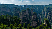 Luftaufnahme der hoch aufragenden Karstsäulen im Zhangjiajie National Forest Park in der chinesischen Provinz Hunan, deren felsige Oberfläche durch das Grün der Bäume aufgeweicht wird.