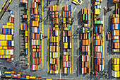 Aerial view of stacked shipping containers in vibrant hues create a geometric tapestry of commerce and trade at the port of La Spezia, Liguria, Italy.