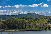 Aerial view of the tranquil waters reflecting the verdant trees, with the snow-capped White Mountains piercing the skyline in the distance, Chania, Chania, Greece.