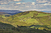 Aerial view of sun-kissed green hills and lush forests create a vibrant tapestry under a sky dotted with fluffy clouds, Látky, Banská Bystrica Region, Slovakia.